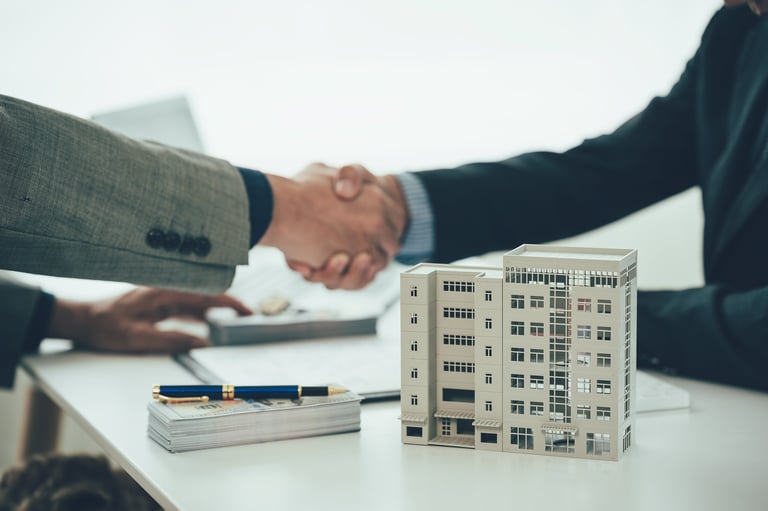 Two businessmen holding hands at the table represents a successful real estate deal. Close up of handshake between real estate agent and new home owner.